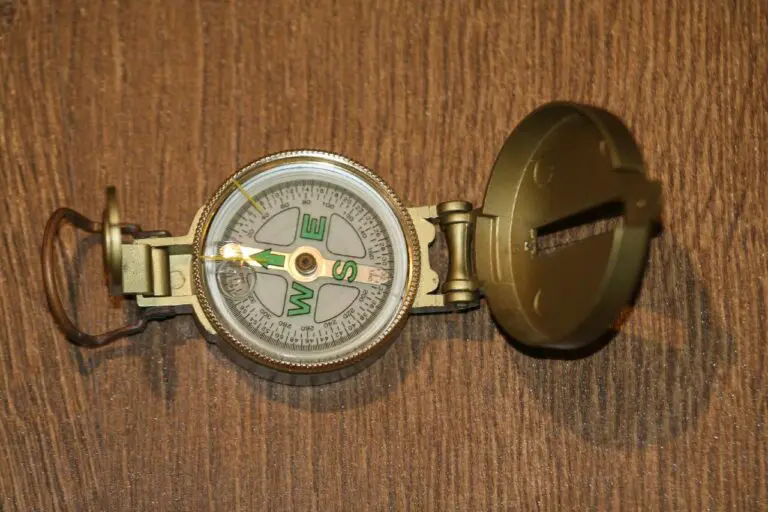 an open antique compass with a wooden table as the background